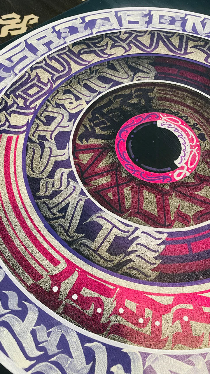 Bottom angle view of THE CALLI DISK – highlighting the bold circular composition and contrast between purple strokes and white script.