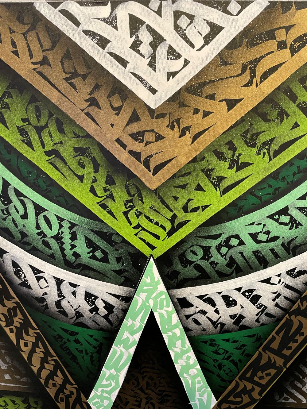 Detailed view of overlapping calligraffiti patterns in green, gold, and white tones